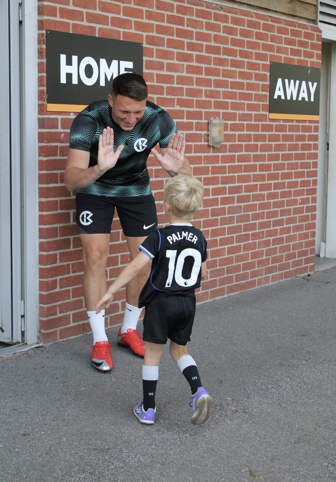 A Bournemouth Ballers coach high-fiving a young player at morning sign-in