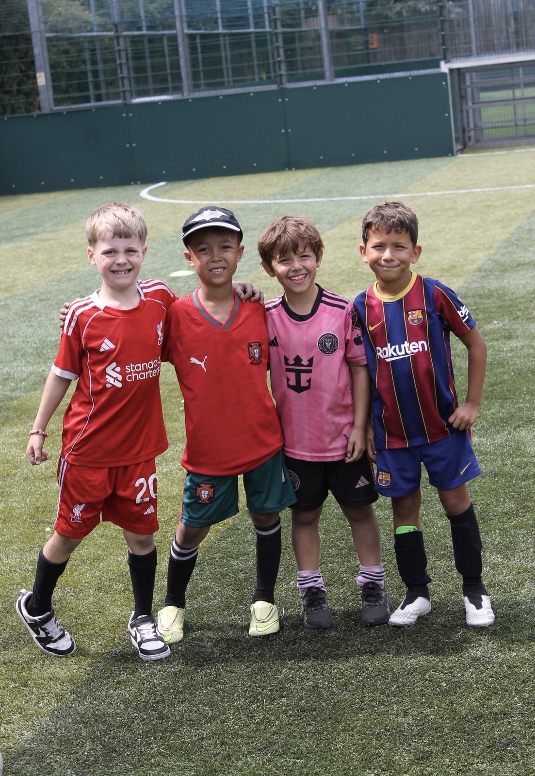 Four young players in their club shirts at a Bournemouth Ballers summer holiday camp