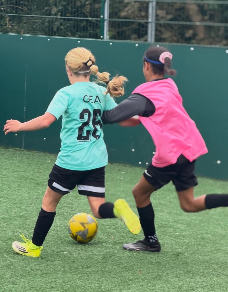 Two girls competing for the ball during a small-sided match at a Bournemouth Ballers girls-only camp in Bournemouth